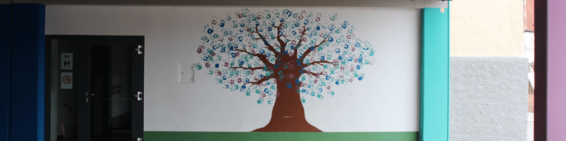 Wandmalerei: Baum mit vielen Handabdrücken als Blätter